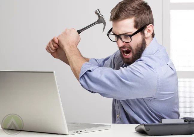 angry-employee-in-glasses-about-to-hit-laptop-with-hammer