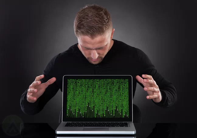 male-hacker-looking-down-on-laptop-with-codes