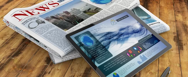 tablet-showing-news-on-top-of-newspaper-stack