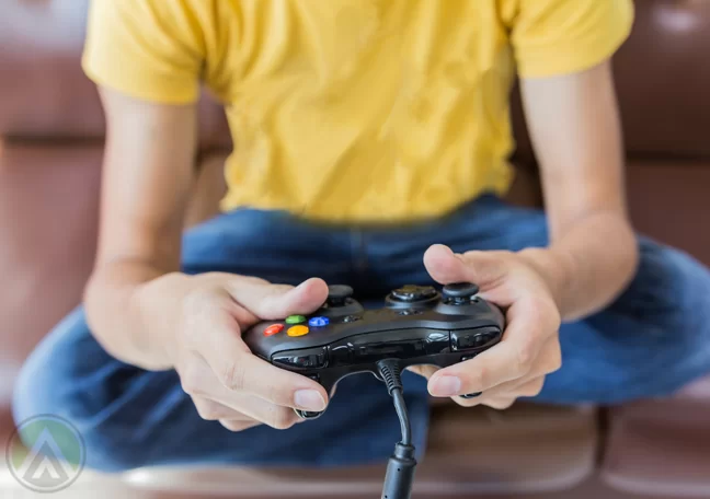 male-teenager-in-yellow-shirt-holding-gaming-controller