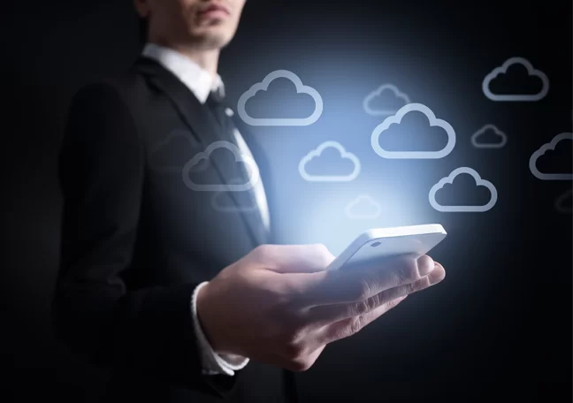 business-executive-using-smartphone-with-cloud-icons-in-dark