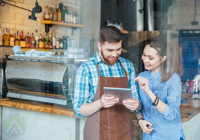 coffee shop barista helping customer with tablet