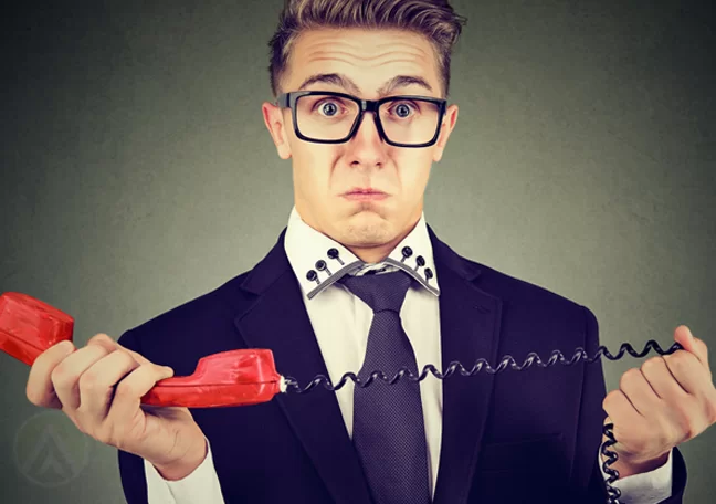 confused businessman holding landline phone receiver