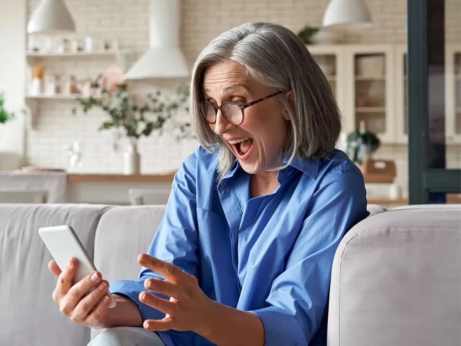 excited woman delighted with good customer experience holding smartphone at home